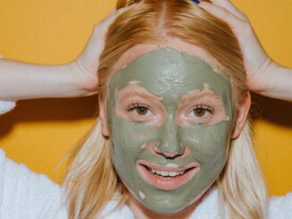 אישה עם מסכת טיפוח ירוקה על הפנים