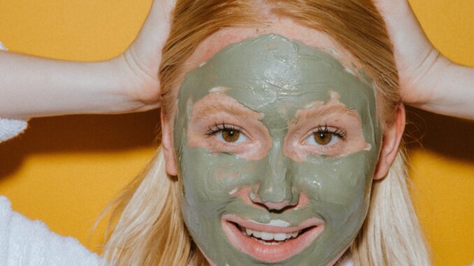 אישה עם מסכת טיפוח ירוקה על הפנים